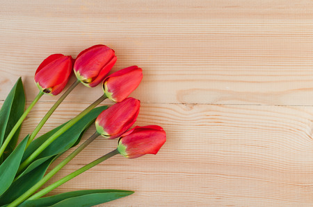 A beautiful bouquet of red tulips on a wooden backgroundの写真素材