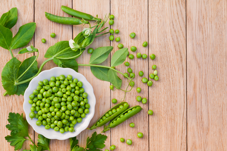 Young green peas on a plate on a wooden backgroundの写真素材