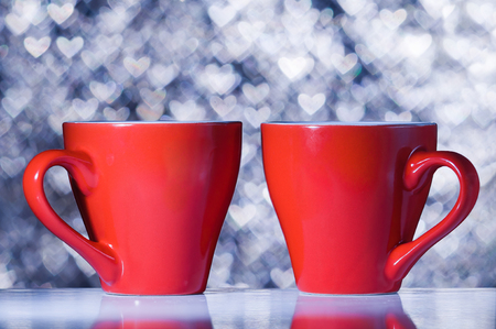 Two red cups on the background bokeh in the shape of heartsの写真素材