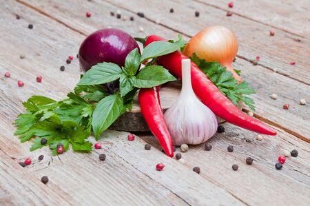 Garlic, onion, hot pepper and herbs on a wooden tableの写真素材