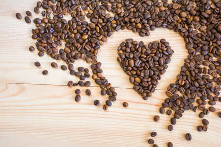 Coffee beans in the shape of a heart on a wooden backgroundの写真素材