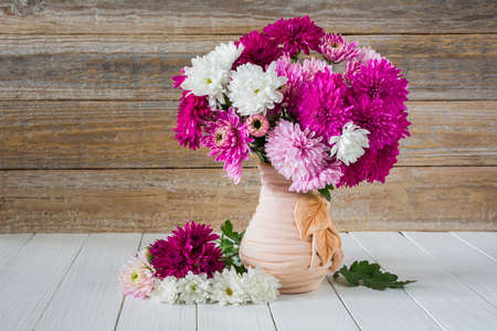 Bouquet of colored chrysanthemums in a vase on a wooden tableの写真素材