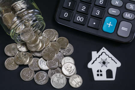 Business concept of finance, savings, mortgage. Model of a house, scattered coins from a glass jar...
