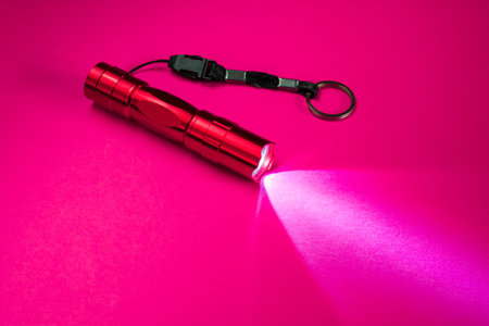 Red pocket flashlight on a red surfaceの写真素材