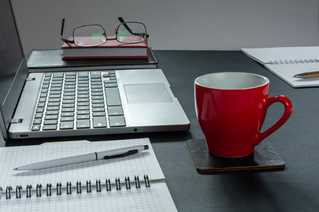Laptop, notepads and a cup of coffee on the desktopの写真素材