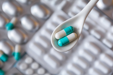 Pills in capsules in a spoon on the background of blister packs of medicinesの写真素材