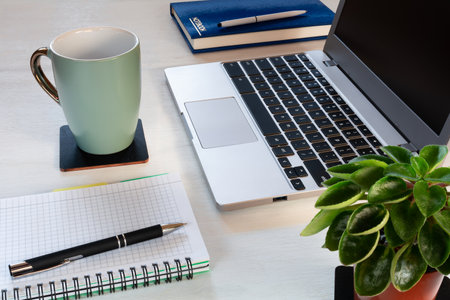 A workplace with a laptop, notebooks and a cup of coffeeの写真素材