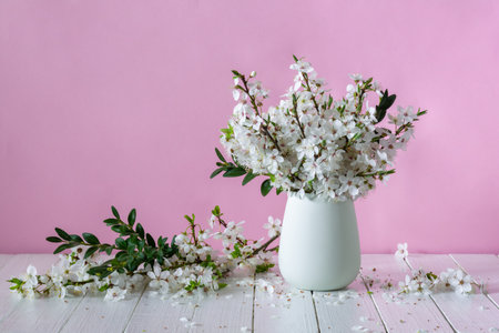 Bouquet of blooming plum branches in a white ceramic vase on a pink background. still lifeの写真素材