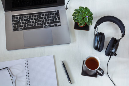 Workplace with laptop, notepad and cup of tea on white desktop