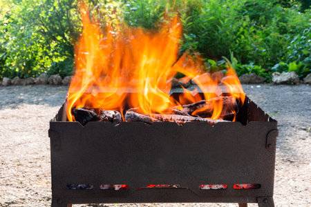 A fire is burning on the grill. Preparation for grilling meat on a picnicの写真素材