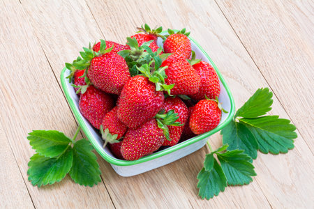 Fresh ripe delicious strawberries in a bowl on a wooden tableの写真素材