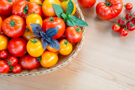 Fresh ripe red and yellow tomatoes in a wicker basket on a wooden table. top viewの写真素材