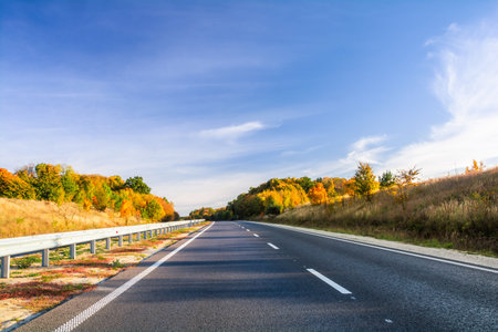 Highway among the autumn forest. Beautiful autumn landscape
