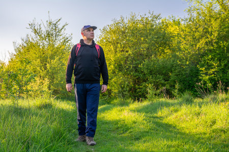 A man walks along a path among trees and green grassの写真素材