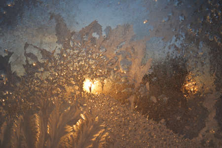Window with frost at dawn in winter