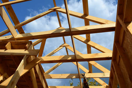 Construction of the roof of a small country house. Wooden rafters and beams on the background of...