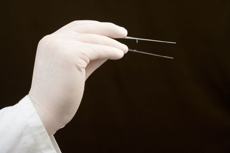 Medical worker holding tweezers against white backgroundの写真素材