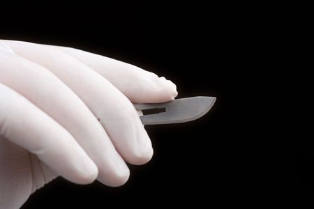 Surgeon holding a blade against black backgroundの写真素材