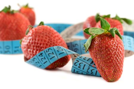 Strawberries with a measure tape against white backgroundの写真素材