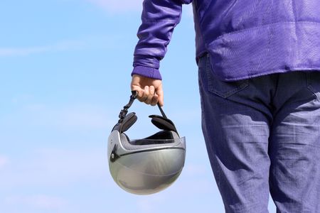 Biker holding a helmet against blue skyの写真素材