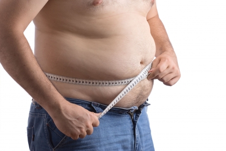 Fat man holding a measurement tape against white backgroundの写真素材