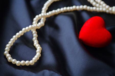 Pearls and red heart on a satin backgroundの写真素材