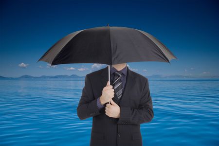 A businessman holding an umbrella covering his faceの写真素材