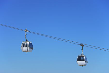 Two air-cable cabins against a blue sky in Lisbon, Portugalの写真素材