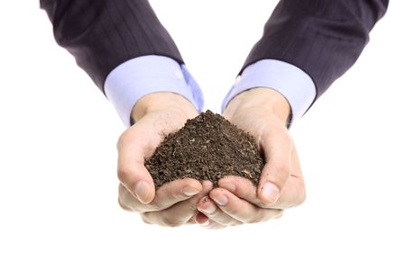 Hands holding a pile of soil isolated against white backgroundの写真素材