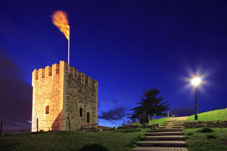 A view of a watchtower with a macedonian flag in Skopje, Macedonia at nightの写真素材