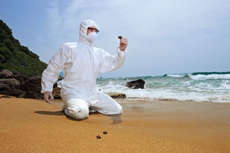 Worker in a protective suit examining pollution at the beachの写真素材