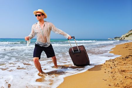 A tourist carrying a suitcase at the beach Peroulades at Corfu island, Greeceの写真素材