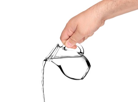 Hand pouring water from pitcher isolated on white backgroundの写真素材