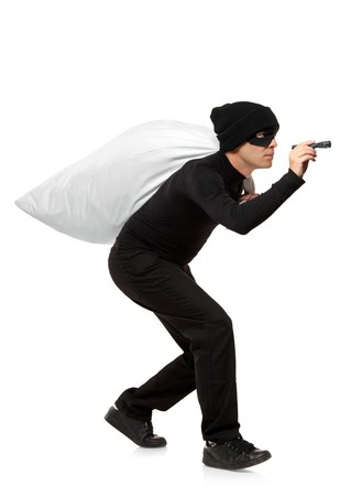 Thief carrying a bag and holding a torch isolated against white backgroundの写真素材