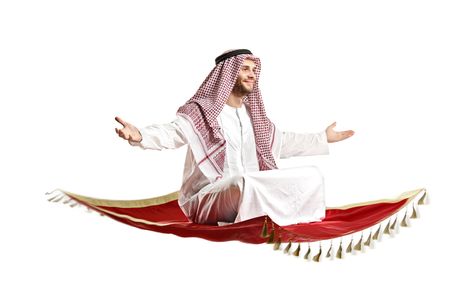 An arab person sitting on a flying carpet isolated on white backgroundの写真素材