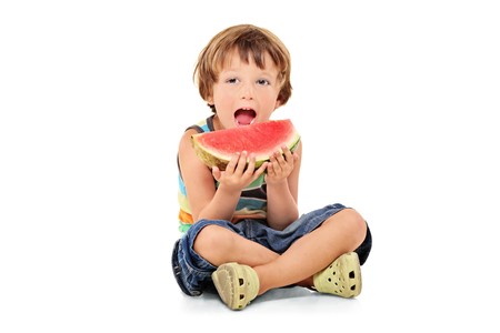 A young boy holding a slice of watermelon isolated against white backgroundの写真素材