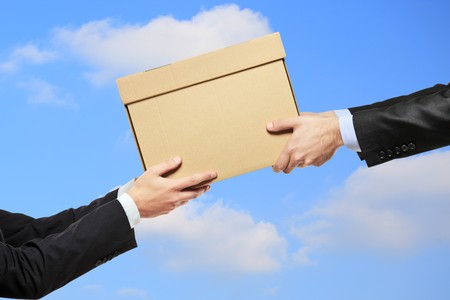 A businessman delivering a package to a man isolated on blue sky with cloudsの写真素材