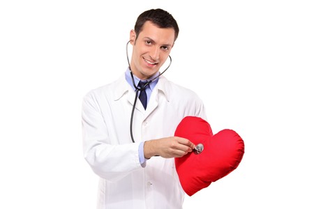 A male doctor examining a red heart shaped pillow with a stethoscope against white backgroundの写真素材