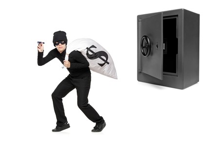 Full length portrait of a thief stealing a money bag from a deposit safe isolated on white...