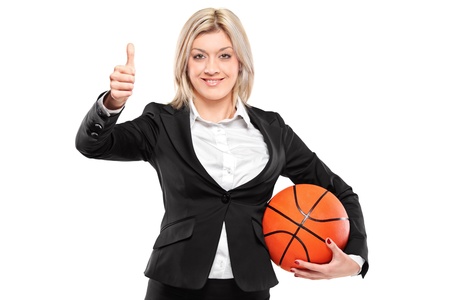 A portrait of a happy businesswoman holding a basketball and giving thumbs up isolated on white backgroundの写真素材