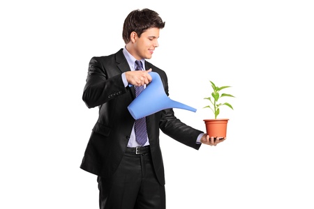 A young businessman pouring a water on a flower isolated on whiteの写真素材