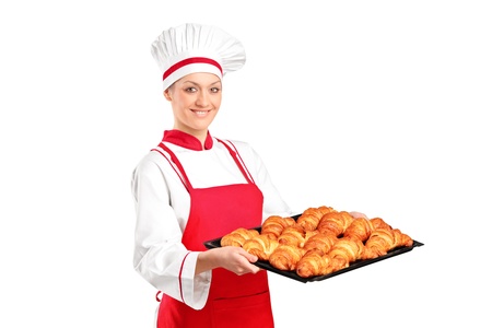 A female baker, wearing red apron, holding freshly baked croissants isolated on white backgroundの写真素材