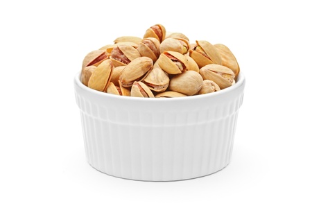 Salted and roasted pistachio nuts in a porcelain bowl isolated on white background の写真素材