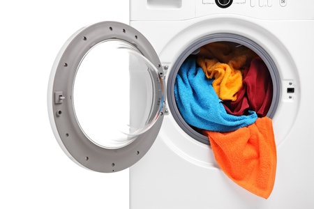 A close up of a washing machine loaded with clothes isolated on white backgroundの写真素材