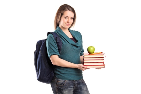 A smiling female student holding books and an apple isolated on white backgroundの写真素材