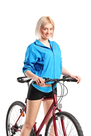 A beautiful smiling female posing next to a bicycle isolated against white backgroundの写真素材