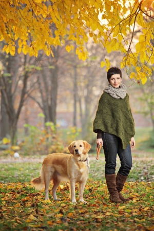 Young girl and her dog (Labrador retriever) walking in autumn in a city park Skopje, Macedoniaの写真素材
