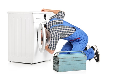 A repairman trying to fix a washing machine isolated on white backgroundの写真素材