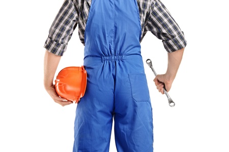 A back view of a repairman in overall holding a wrench and helmet isolated on white background