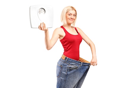Portrait of a weight loss female holding a weight scale isolated on white backgroundの写真素材